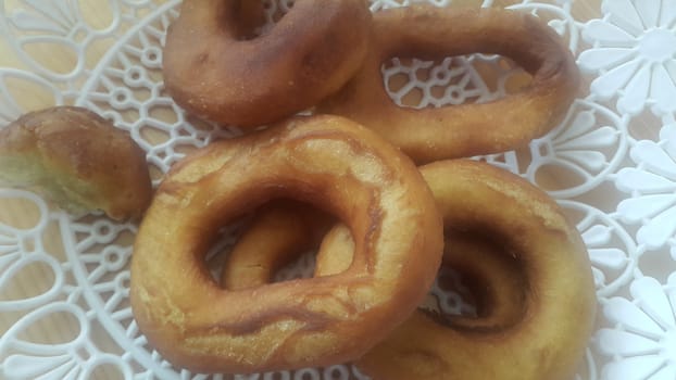 Closeup view of a set of freshly prepared donuts served on white changair. Donuts are placed in a changair over wooden floor