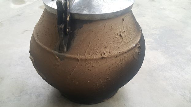 Pressure cooker covered with mud for cooking on fire. Cauldron type rural pressure cooker.