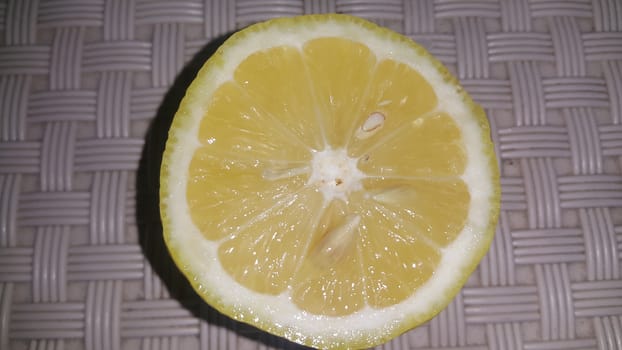 Fresh lemon slices with yellow peelings placed on a grey floor. Top view of fresh juicy lemon slice background