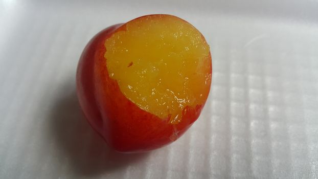 Closeup view of red plum on a white grey background. Freshly harvested plum making heart shape appearance in the view from angle.