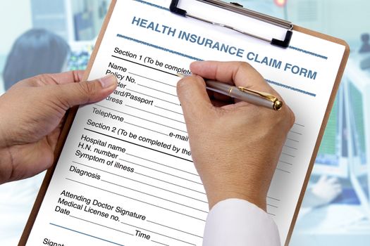 Someone writting personal information into blank health insurance form on clipboard.