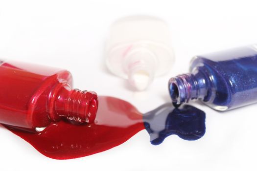 Red, White and Blue Nail Polish Spilled on White Background