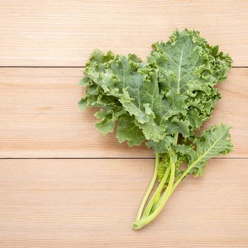 Fresh organic curly kale leaves flat lay on a wooden table with copy space.