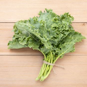 Fresh organic curly kale leaves flat lay on a wooden table with copy space.