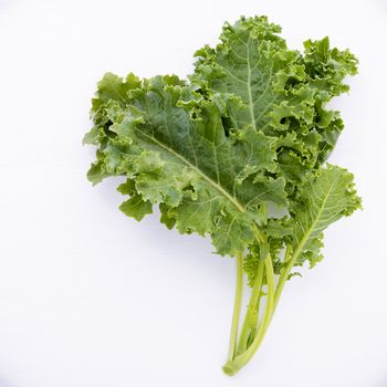 Fresh organic curly kale leaves flat lay on a wooden table with copy space.