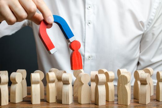 businessman pulls out a red figure of a man from the crowd with the help of a magnet. leader manages the business and forms a team. toxic, incompetent worker. Increase team efficiency, productivity.