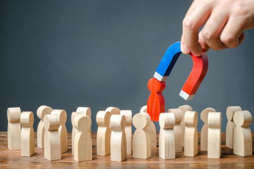 businessman pulls out a red figure of a man from the crowd with the help of a magnet. Increase team efficiency, productivity. leader manages the business and forms a team. toxic, incompetent worker.