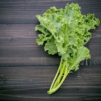 Fresh organic curly kale leaves flat lay on a wooden table with copy space.