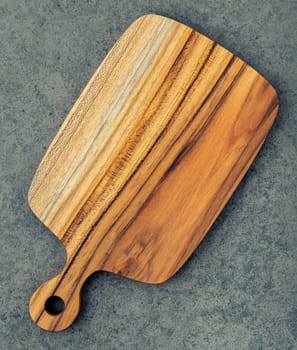 Chopping teak wood cutting board on dark stone background.