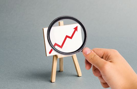 Magnifying glass is looking at the Rack with a red arrow up. Business planning and revenue analysis. Indicators of business projects, level of profitability. Increase efficiency. Selective focus