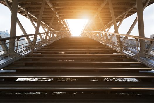 Stairs of solferino pedestrian bridge over river Seine against sun in Paris, France