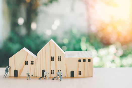 Miniature people or small model human figure cleaning with wooden home with green nature bokeh background.