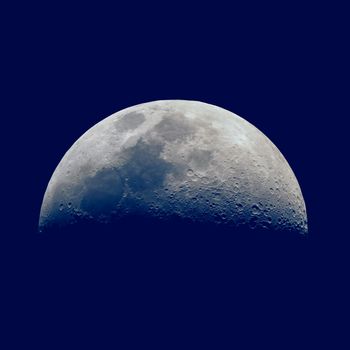 First quarter moon seen with an astronomical telescope, dark blue sky