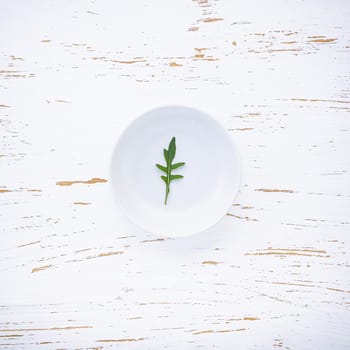 Food background and salad concept with wild rocket flat lay on white wooden background.
