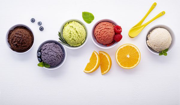 Various of ice cream flavor ball blueberry ,lime ,pistachio ,almond ,orange ,chocolate and vanilla set up on white wooden background . Summer and Sweet menu concept.