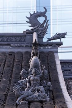 Dragon sculpture on Daci buddhist temple roof against modern building in Chengdu, China