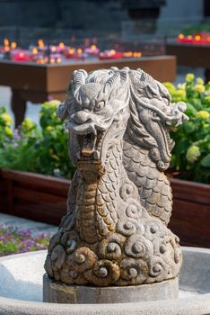 Dragon sculpture in a fountain in Daci buddhist temple roof against modern building in Chengdu, China