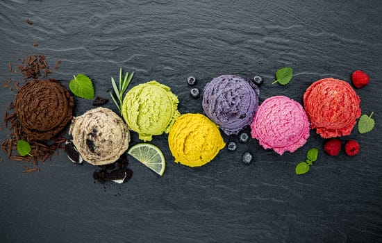 Various of ice cream flavor ball blueberry ,lime ,pistachio ,almond ,orange ,chocolate and vanilla set up on dark stone background . Summer and Sweet menu concept.