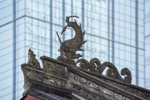 Dragon sculpture on Daci buddhist temple roof against modern building in Chengdu, China