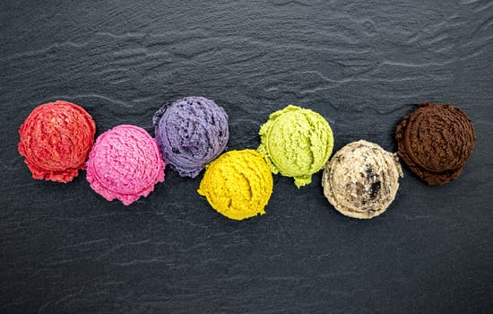 Various of ice cream flavor ball blueberry ,lime ,pistachio ,almond ,orange ,chocolate and vanilla set up on dark stone background . Summer and Sweet menu concept.