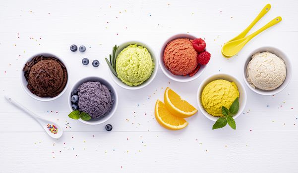 Various of ice cream flavor ball blueberry ,lime ,pistachio ,almond ,orange ,chocolate and vanilla set up on white wooden background . Summer and Sweet menu concept.