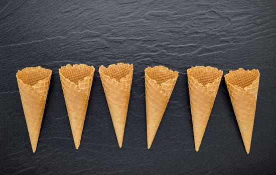 Flat lay ice cream cones collection on dark stone background . Blank crispy ice cream cone with copy space for sweets menu design.