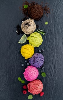 Various of ice cream flavor ball blueberry ,lime ,pistachio ,almond ,orange ,chocolate and vanilla set up on dark stone background . Summer and Sweet menu concept.