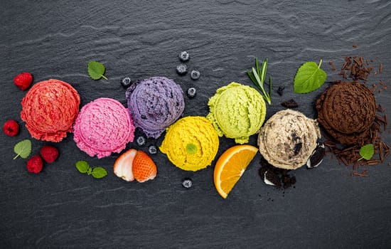 Various of ice cream flavor ball blueberry ,lime ,pistachio ,almond ,orange ,chocolate and vanilla set up on dark stone background . Summer and Sweet menu concept.