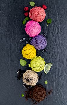 Various of ice cream flavor ball blueberry ,lime ,pistachio ,almond ,orange ,chocolate and vanilla set up on dark stone background . Summer and Sweet menu concept.