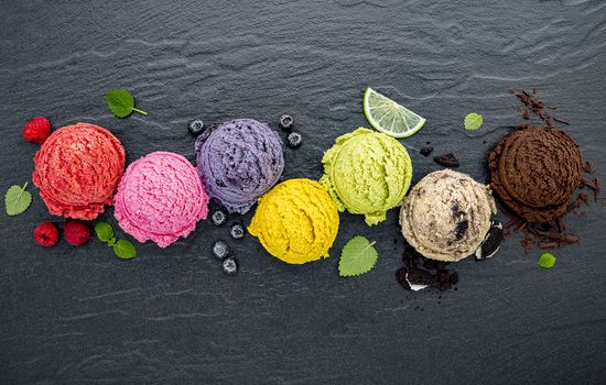 Various of ice cream flavor ball blueberry ,lime ,pistachio ,almond ,orange ,chocolate and vanilla set up on dark stone background . Summer and Sweet menu concept.