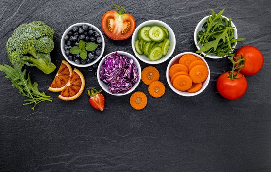 Colourful ingredients for healthy smoothies and juices on dark stone background with copy space.