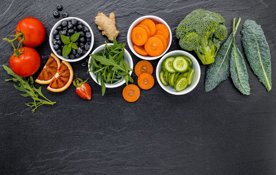 Colourful ingredients for healthy smoothies and juices on dark stone background with copy space.