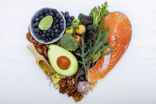 Heart shape of ketogenic low carbs diet concept. Ingredients for healthy foods selection on white wooden background. Balanced healthy ingredients of unsaturated fats for the heart and blood vessels.