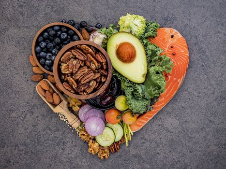 Heart shape of ketogenic low carbs diet concept. Ingredients for healthy foods selection on dark stone background. Balanced healthy ingredients of unsaturated fats for the heart and blood vessels.