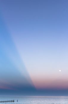 Abstract and dramatic sunset with light rays that create the shape of an inverted pyramid on the sea.
