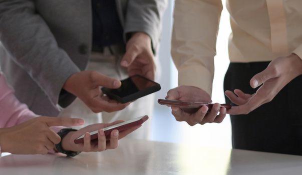 Many employees hold their smartphones near each other to exchange wireless data.