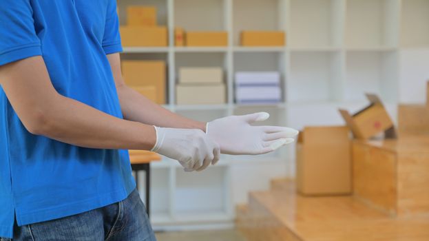 The parcel delivery staff is wearing gloves to prevent infection during delivery.