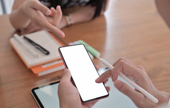 Cropped shot of a young woman pointing a smartphone in her friends hand to suggest usage.