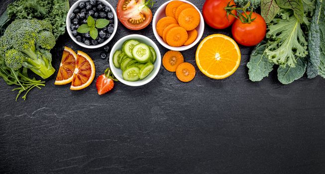 Colourful ingredients for healthy smoothies and juices on dark stone background with copy space.