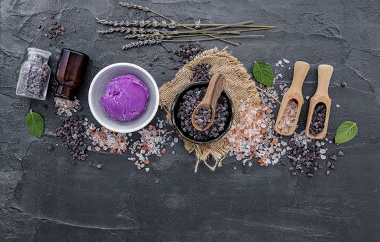 Himalayan black salt and Himalayan pink salt with peppermint and lavender flower on dark concrete background. Himalayan salt commonly used in cooking and for bath products such as bath salts.