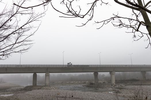 Large highway viaduct with foggy day on autumn. Regular traffic.