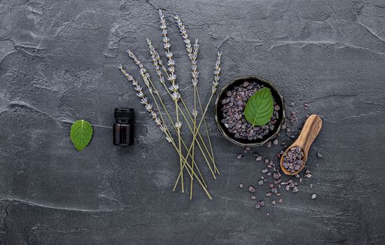 Himalayan black salt and Himalayan pink salt with peppermint and lavender flower on dark concrete background. Himalayan salt commonly used in cooking and for bath products such as bath salts.