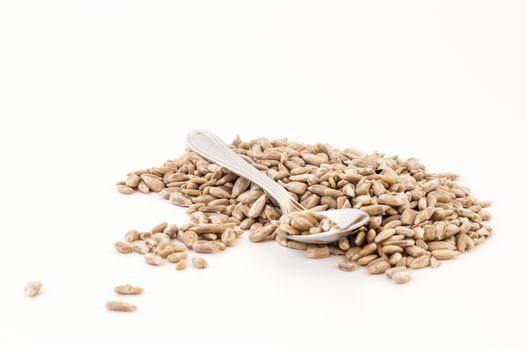 Natural shelled sunflower seeds with small spoon over white background. Shallow depth of field.