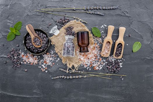 Himalayan black salt and Himalayan pink salt with peppermint and lavender flower on dark concrete background. Himalayan salt commonly used in cooking and for bath products such as bath salts.