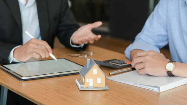 Close up shot of Customers are listening to promotions from home brokers. With model houses and tablet on the table.