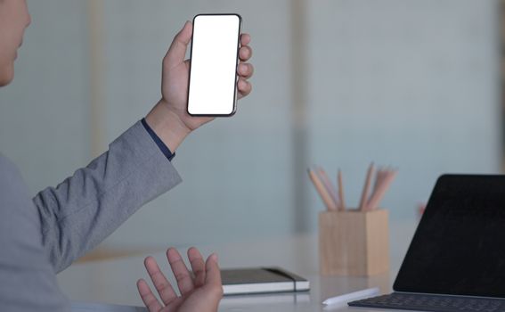 Cropped shot of A young executive holds a smartphone for online video calling in a modern personal office.