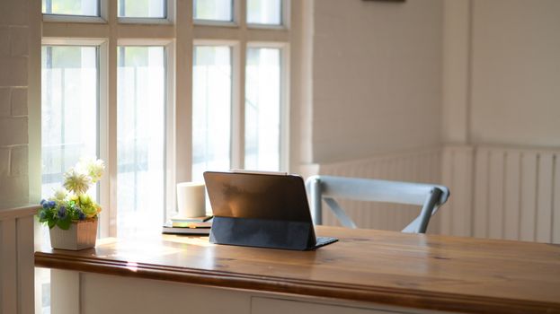 Laptop with a notebook and coffee on a wooden table in the office with beautiful lighting.