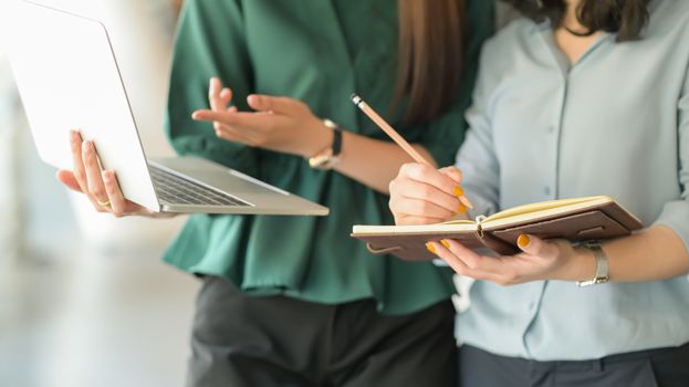 A quality business team is using the laptop and taking notes to present the project to customers.