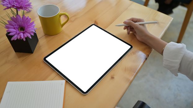 Close up shot of a girl holding a pen and using a blank screen tablet.