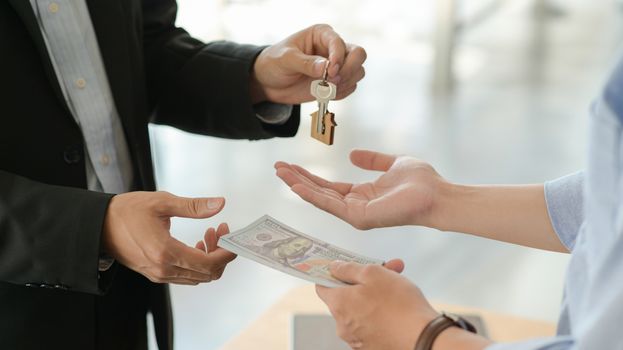 Customers and landlords exchange money and keys after agreeing to buy a house.